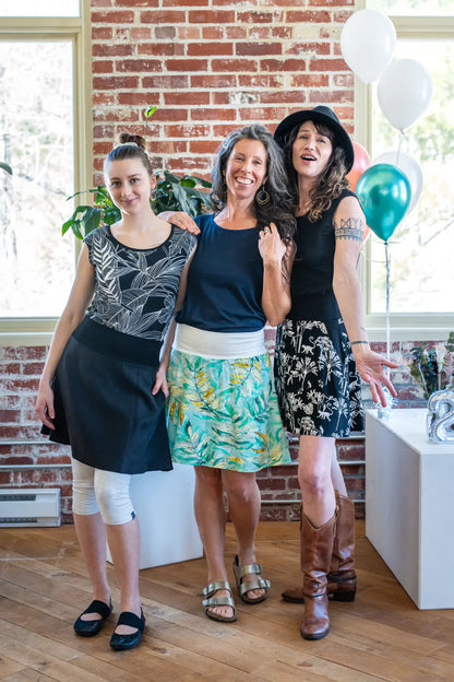 Three women wearing the Soleil Skirt by Marie C, with Sol Tops, standing indoors at a party. 