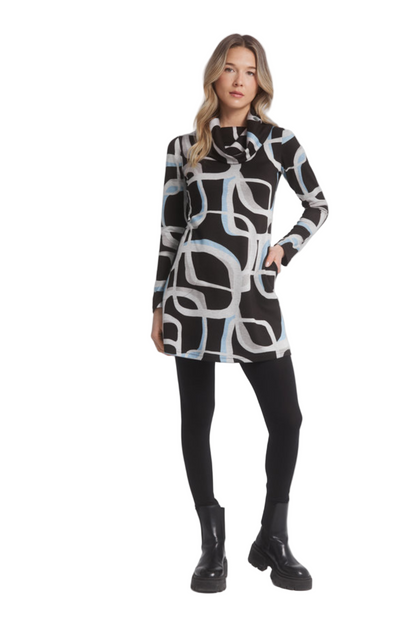 A woman wearing the Eve Tunic by Dinh Ba in Blue geometric print, a long sleeved tunic with a large cowl neck and an A-line shape. She is standing in front of a white background. 