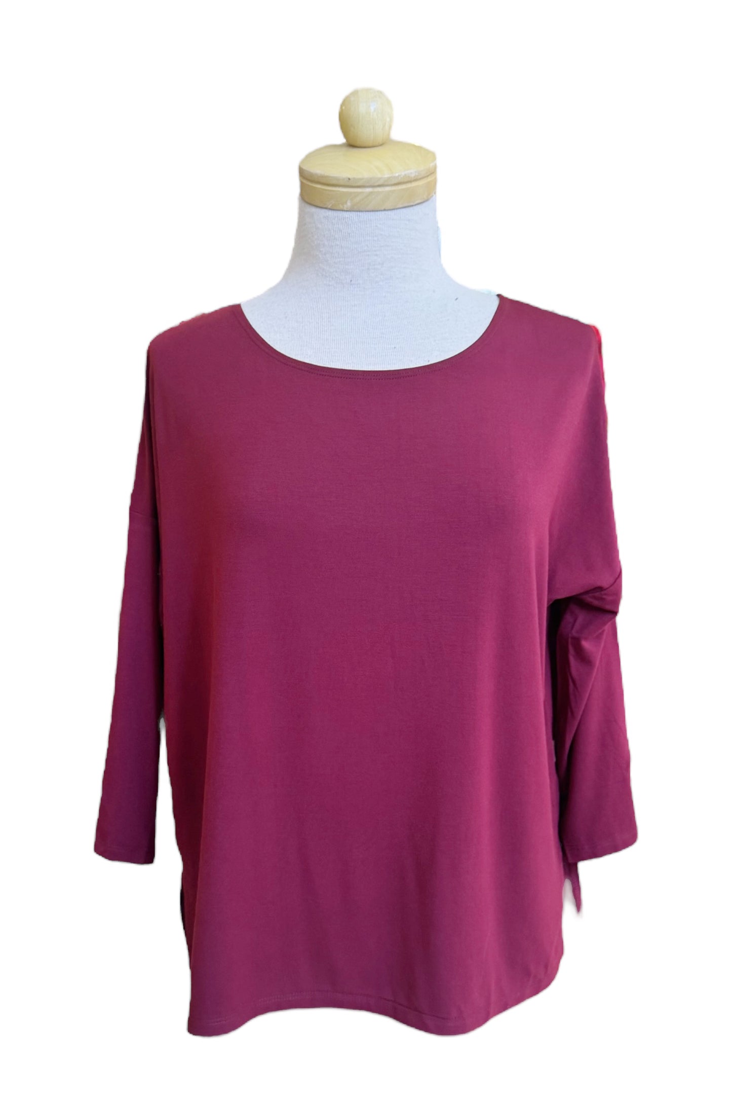 The Emmy Top by Moovment in Burgundy, with a boat neck, 3/4 sleeves, and side slits, is shown on a mannequin in front of a white background. 