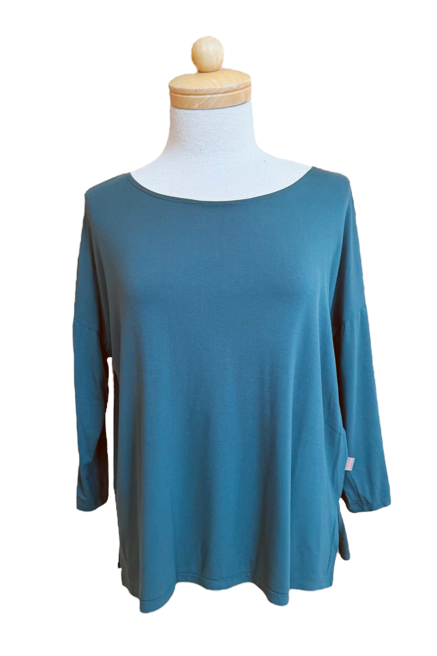 The Emmy Top by Moovment in Teal, with a boat neck, 3/4 sleeves, and side slits, is shown on a mannequin in front of a white background. 