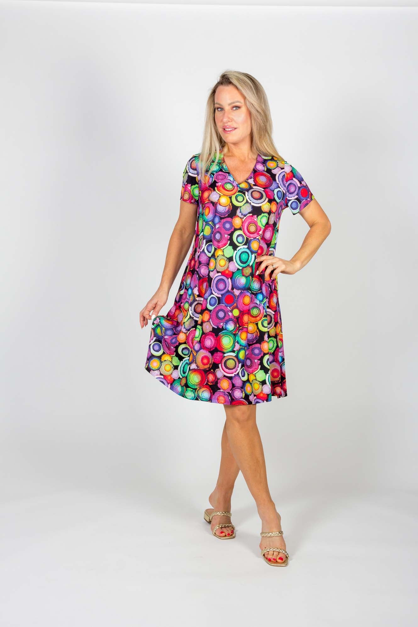A woman wearing the Chase Dress by Pure Essence featuring a multicolour circles pattern, standing in front of a white background
