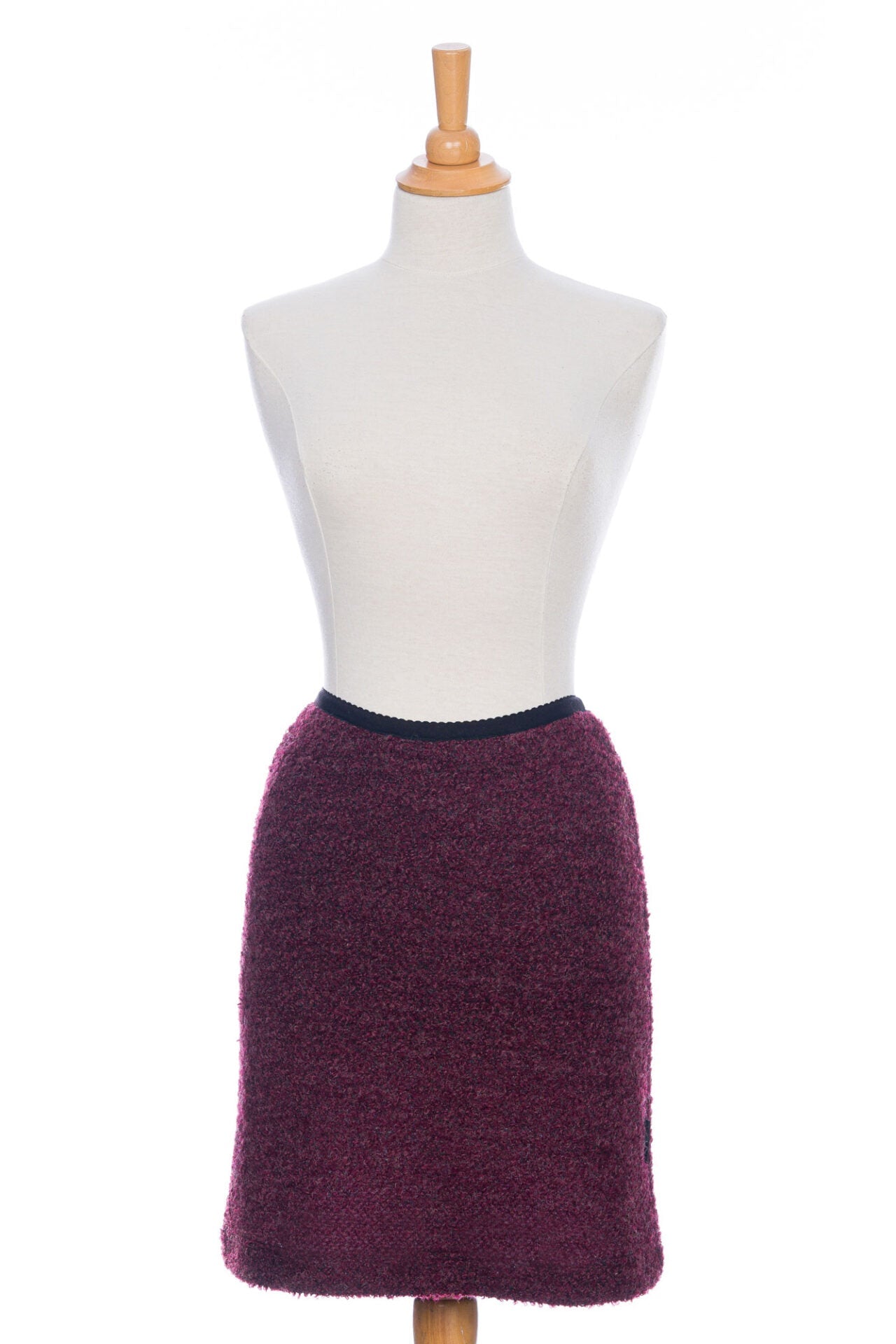 A front view of the Rhododendron Skirt by Rien ne se Perd in Merlot, a straight cut boucle skirt with an elastic waistband and a hem that hits above the knee, is shown on a mannequin in front of a white background.