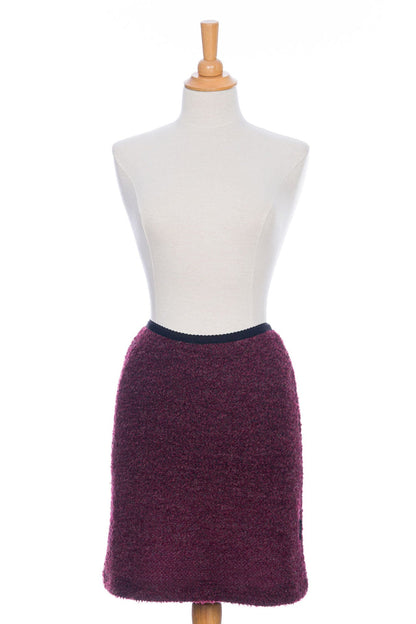 A front view of the Rhododendron Skirt by Rien ne se Perd in Merlot, a straight cut boucle skirt with an elastic waistband and a hem that hits above the knee, is shown on a mannequin in front of a white background.