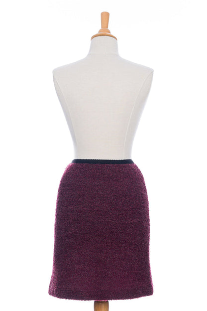 A back view of the Rhododendron Skirt by Rien ne se Perd in Merlot, a straight cut boucle skirt with an elastic waistband and a hem that hits above the knee, is shown on a mannequin in front of a white background.