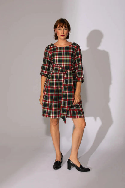 A woman wearing the Do You Realize Dress by Eve Lavoie in White and Navy Tartan, standing in front of a white background 