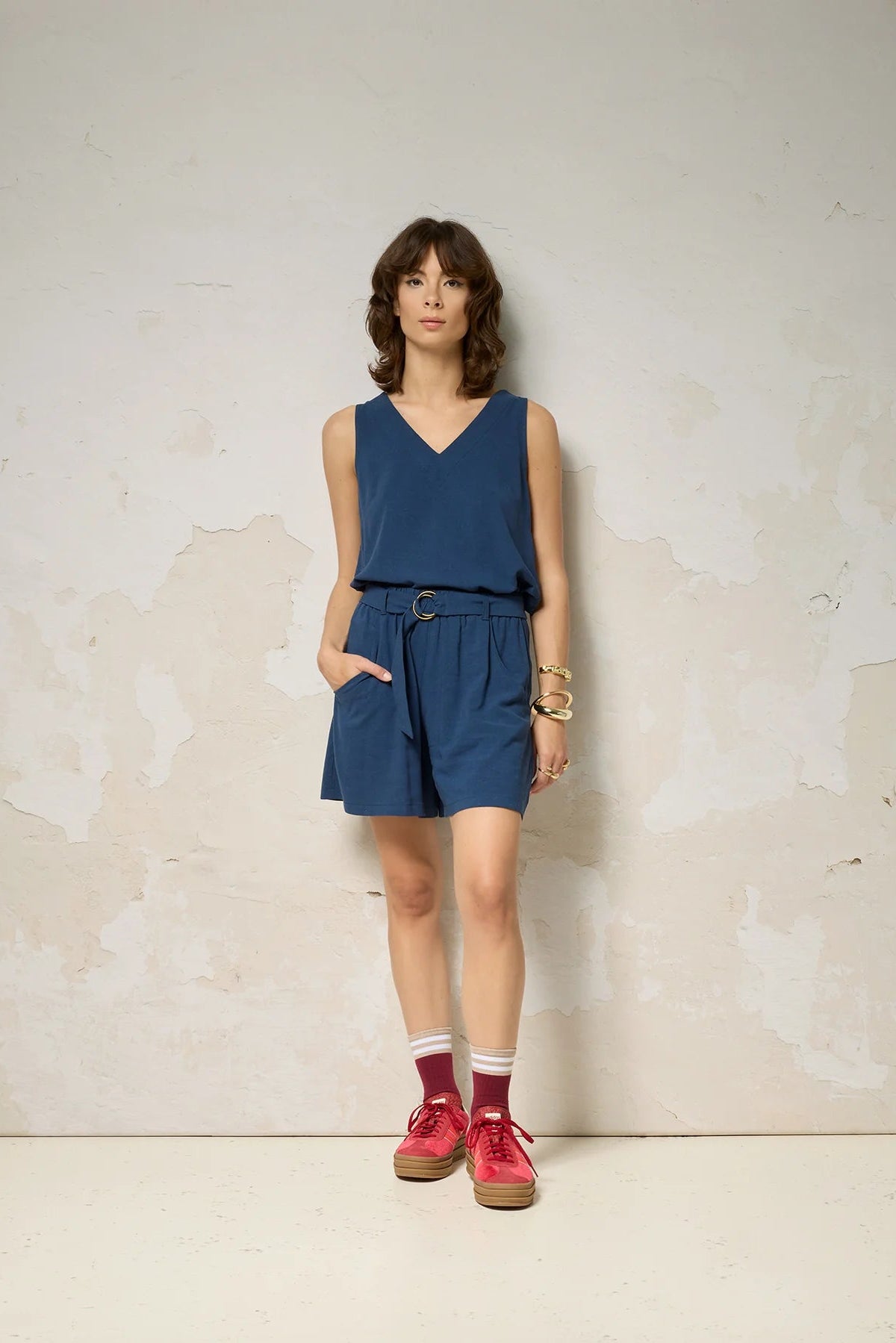 A woman wearing the Sita Top by Cokluch in Denim print, a sleeveless V-neck tank with a loose fit and wide straps. She is wearing it with matching shorts against a plain background