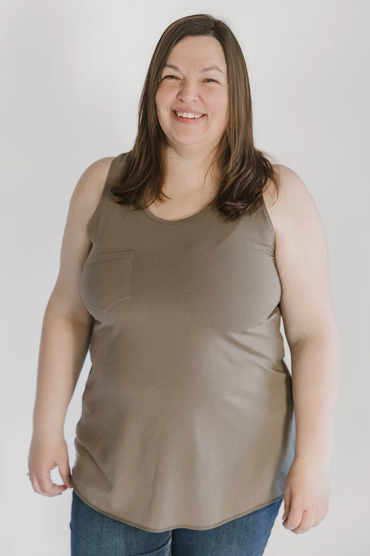 A woman wearing the Sunset Tank by Blondie Apparel in Stone, standing in front of a white background