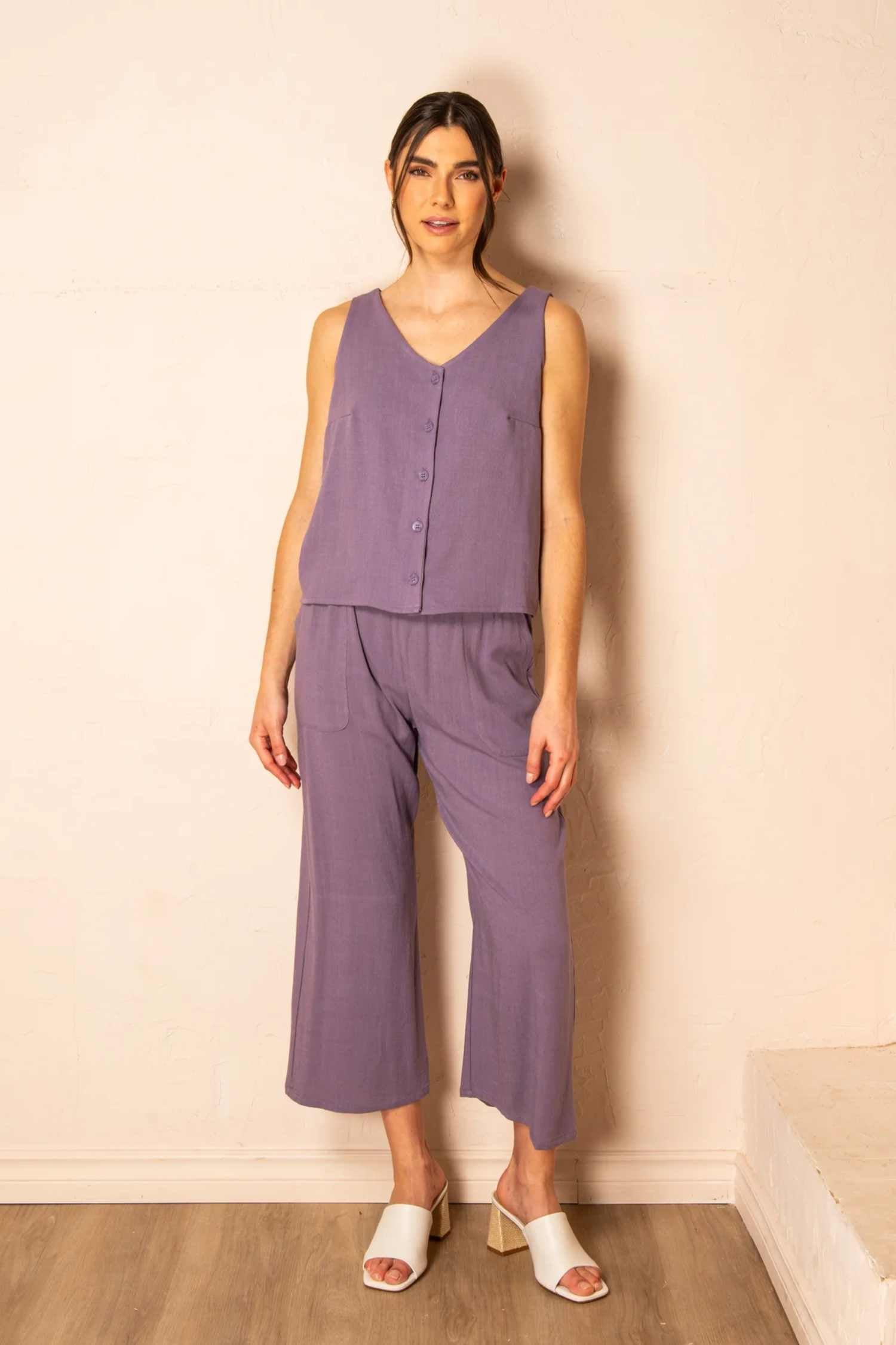 Photo of a woman wearing the Serenity Pants by Cherry Bobin in Mauve, standing in front of a wall 