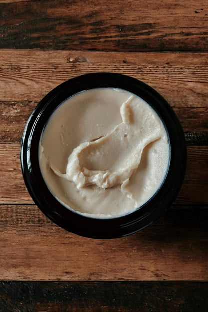 An open jar of 'Rose Remedy' ultra rich face cream by Stay Wild Apothecary is shown on a wooden surface