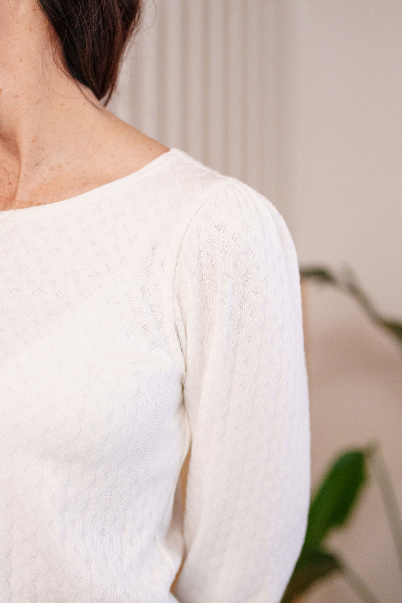 Detail of the Camarine Sweater by Rien ne se Perd in Ivory, a cable knit sweater with a scooped neck, puffed shoulders, and gathered cuffs.