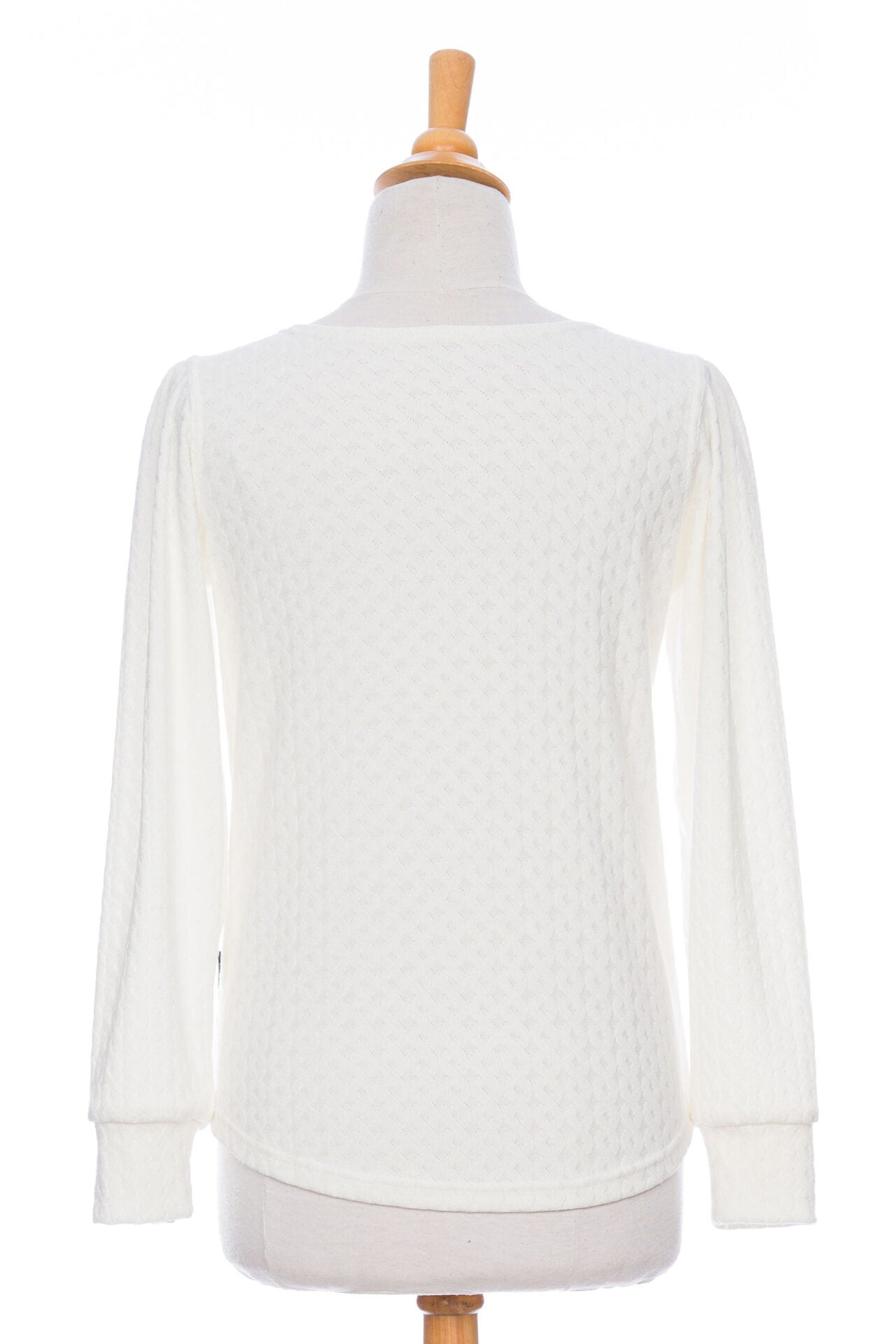 Back view of the Camarine Sweater by Rien ne se Perd in Ivory, a cable knit sweater with a scooped neck, puffed shoulders, and gathered cuffs, shown on a mannequin agains a white background. 