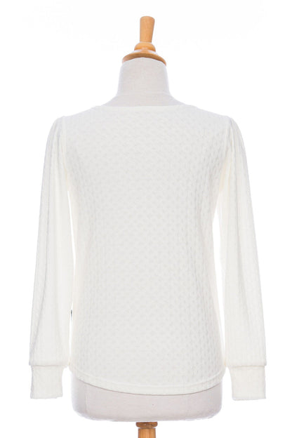 Back view of the Camarine Sweater by Rien ne se Perd in Ivory, a cable knit sweater with a scooped neck, puffed shoulders, and gathered cuffs, shown on a mannequin agains a white background. 