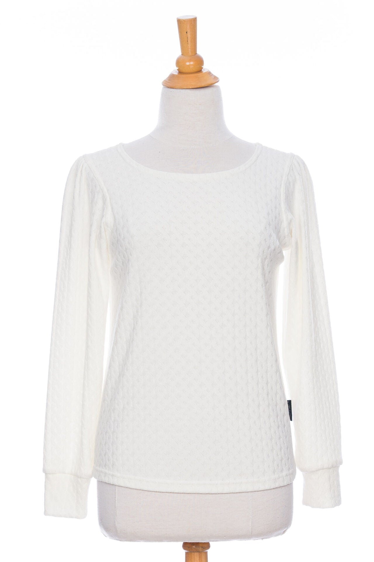 The Camarine Sweater by Rien ne se Perd in Ivory, a cable knit sweater with a scooped neck, puffed shoulders, and gathered cuffs, shown on a mannequin agains a white background. 