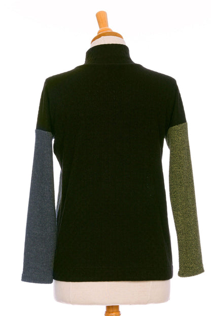 A back view of the Chèvrefeuille Sweater by Rien ne se Perd in Sage, a multi-toned piece that's green on the right side, grey on the left, with a black back, is shown on a mannequin in front of a white background.  It has a cross-over front with five black buttons. 