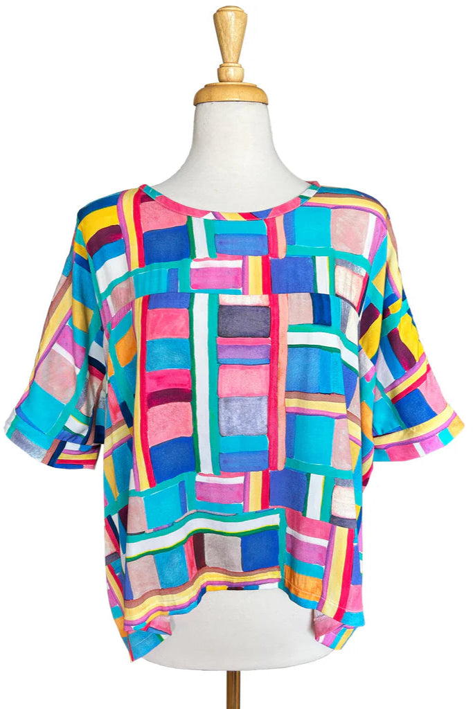 The Chloe Top by Desserts and Skirts in Bloc Party print, featuring a round neck, batwing sleeves, and a loose and flowing fit, shown on a mannequin against a white background