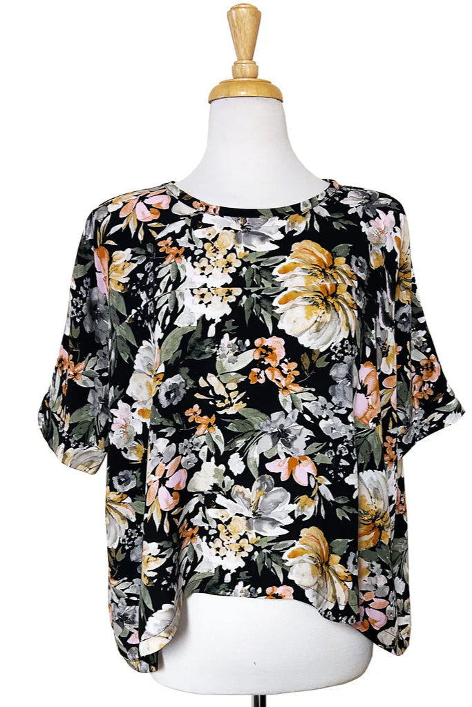 The Chloe Top by Desserts and Skirts in Butter Floral print, featuring a round neck, batwing sleeves, and a loose and flowing fit, shown on a mannequin against a white backgroundFloral blouse on a mannequin against a white background