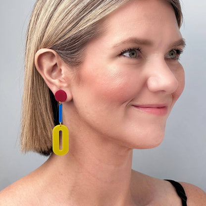 Woman wearing colorful earrings against a neutral background