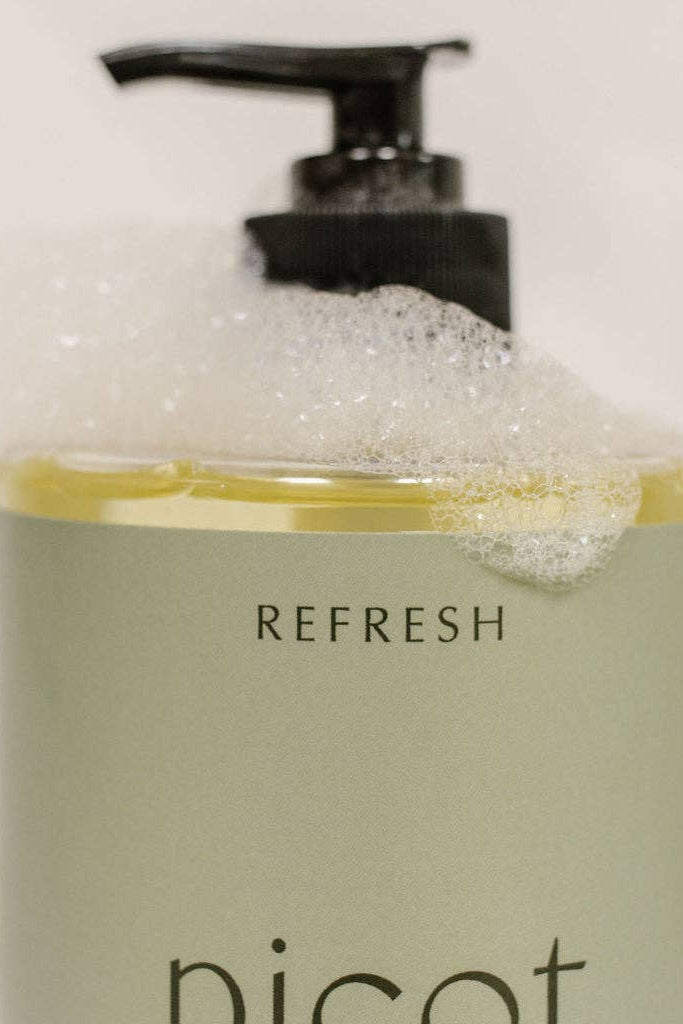 Close up of Picot's Refresh hand, bath & body wash pump bottle with lather on it, on a white background