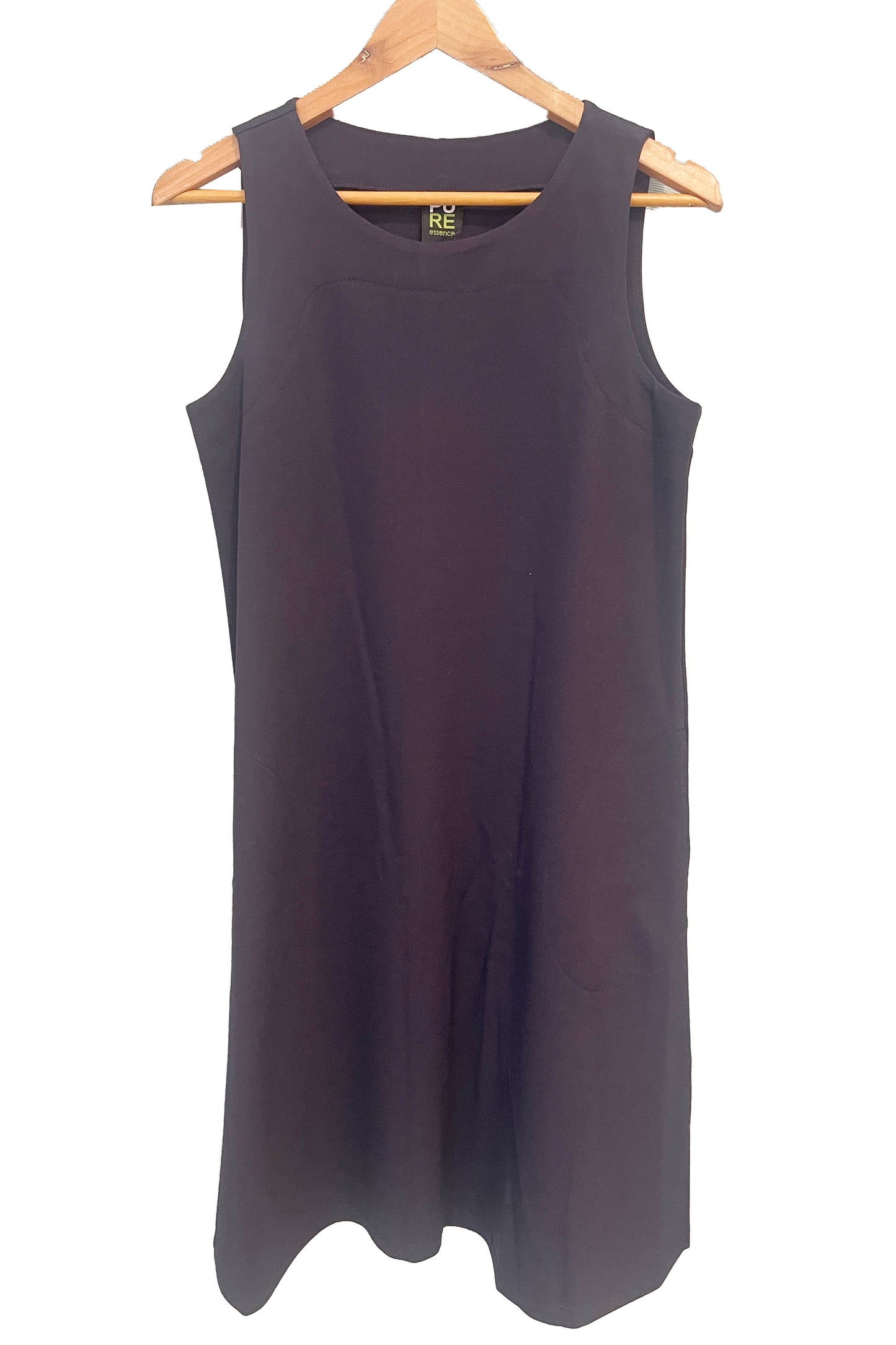 The Felicity Dress by Pure Essence in Navy, a sleeveless dress with a round neck, an a-line shape, and a knee length hem, is shown hanging in front of a white wall. 