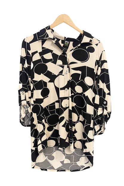 The Francesca Blouse by Pure in Black/Ivory geometric print, an oversized blouse with a lapel collar, button front, 3/4 sleeves with button and tab detail, and rounded h-low hemline, is shown hanging against a white background. 