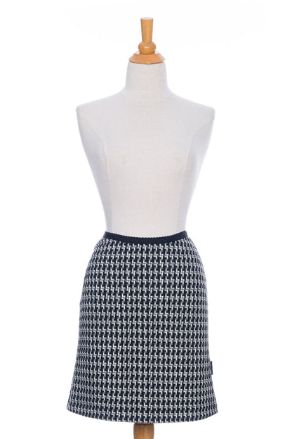 The Meleze Skirt by Rien ne se Perd in Black and White houndstooth, a knee-length straight skirt with an elastic waist, is shown on a mannequin in front of a white background. 