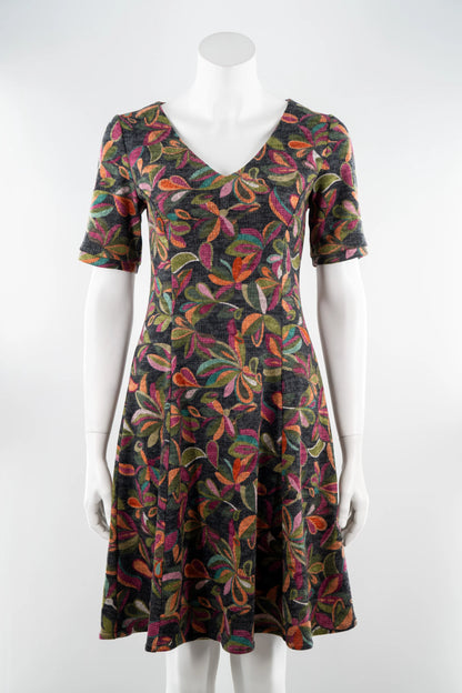 The Botanical Dress by Karkass in Floral, a knit dress with a V-neck, elbow length sleeves, fit and flare shape, and above the knee hem, is shown on a mannequin in front of a white background. 