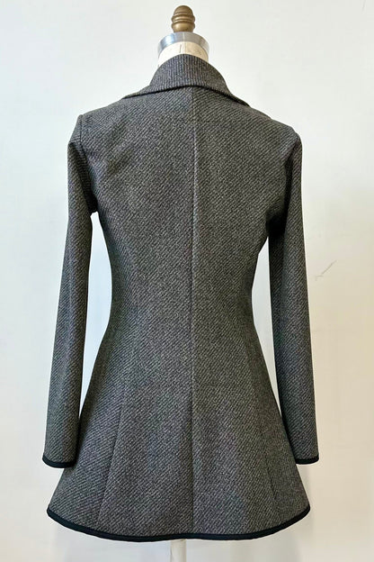 Back view of the Henderson Jacket by Kollontai in Charcoal tweed, with a fitted A-line shape that flares from the waist, a classic collar, and buttons down the front, shown on a mannequin in front of a white background. 