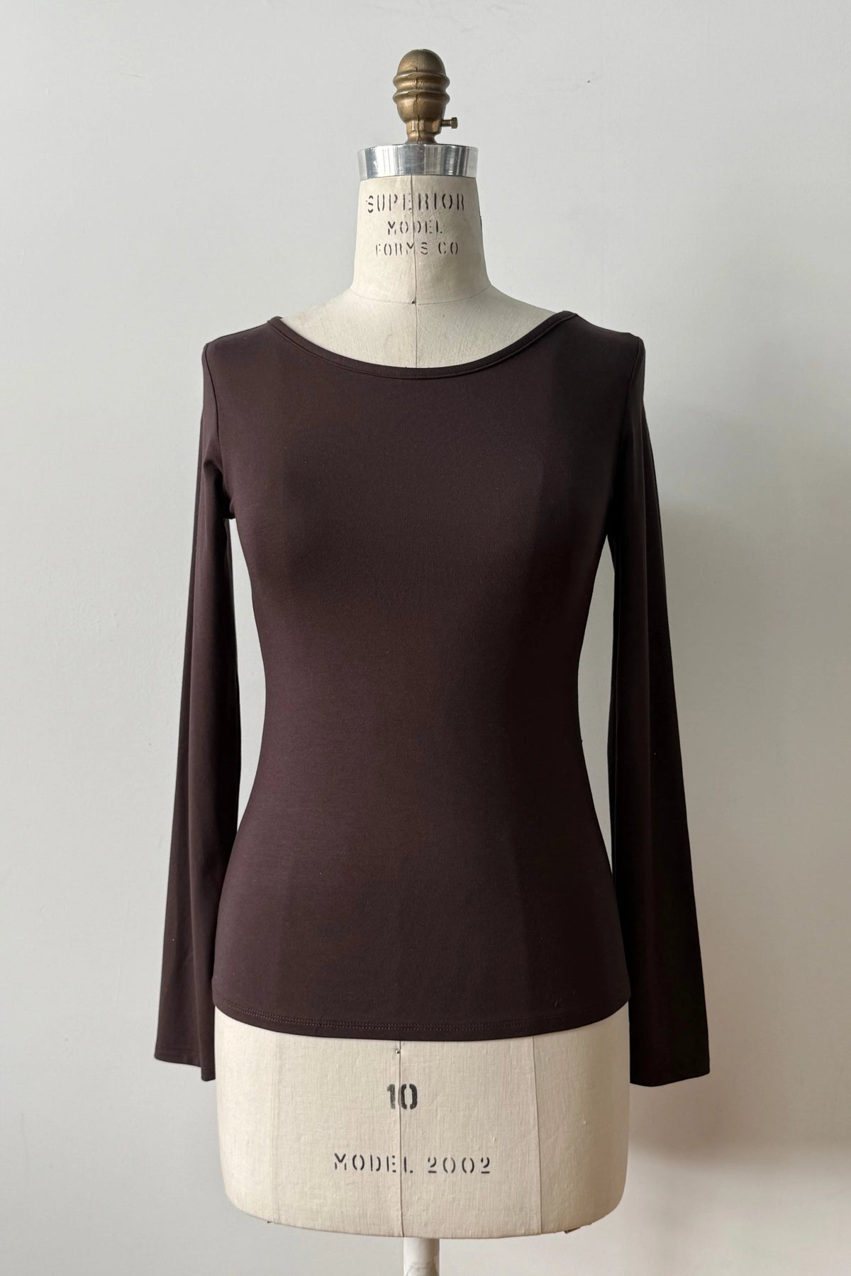 The Loretto Top by Kollontai in Chocolate, a slim fitting long sleeved top with a round neck, is shown on a mannequin against a white background. 