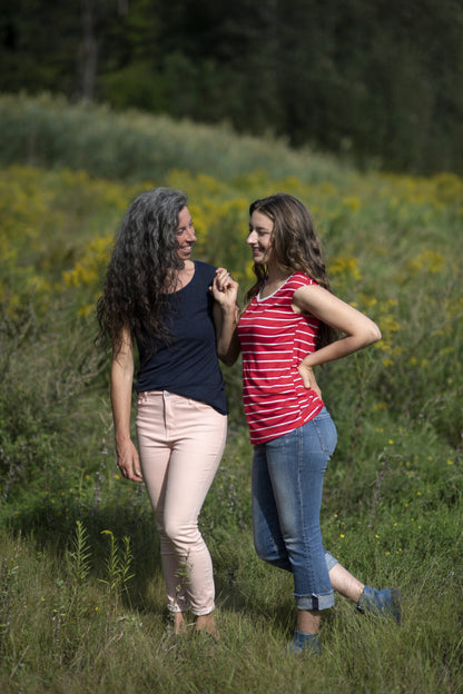 Two women wearing the Sol Top by Marie C, one in Navy and one in Red Stripe, with a scoop neck and cap sleeves. They are standing in a field. 