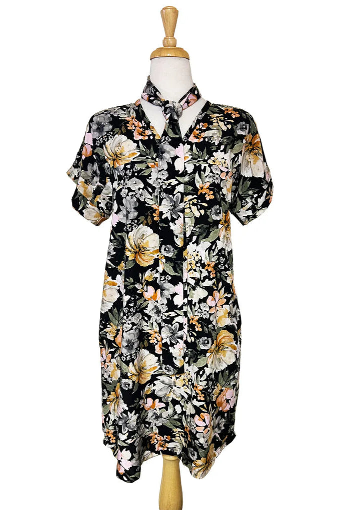 The Olivia Dress by Desserts and Skirts in Butter Floral, featuring short sleeves, a V-neck, a removable belt, and a knee length hem, is show on a mannequin in front of a white background. 