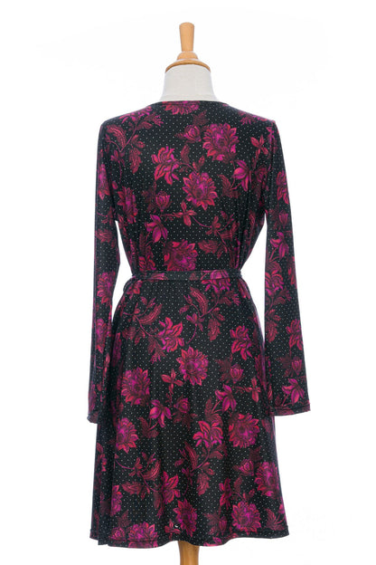 A back view of the Epilobe Dress by Rien ne se Perd in Polka Dots and Roses, a classic wrap dress with a tie at the waist, delicate pleats at the shoulders, and a hem that hits above the knee, is shown on a mannequin in front of a white background. 