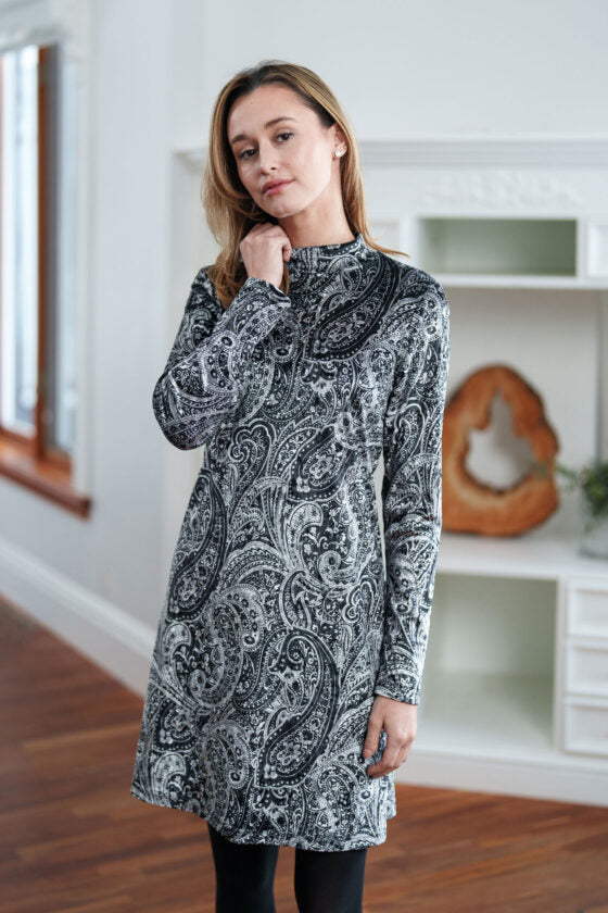 A woman wearing the Frida Dress by Rien ne Perd in Black and White Velvet stands in front of a white cabinet 