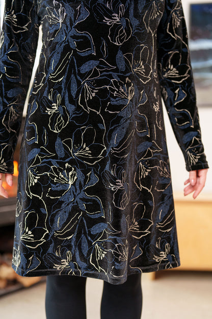 Close up detail of a woman wearing the Larix Dress by Rien ne se Perd in Black/Navy/Gold, a velvet dress with a floral pattern, a round neck, an a knee-length A-line shape.