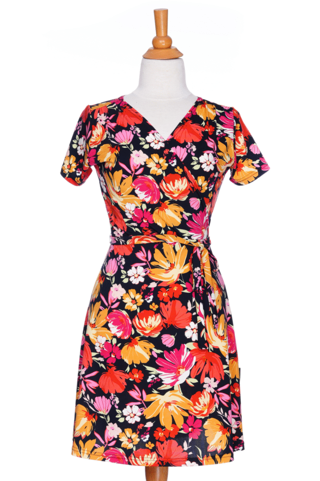 The Margarita Dress by Rien ne se Perd in Red/Orange floral print, with a faux wrap neckline, short sleeves, and short a-line skirt, is shown on a mannequin in front of a white background.