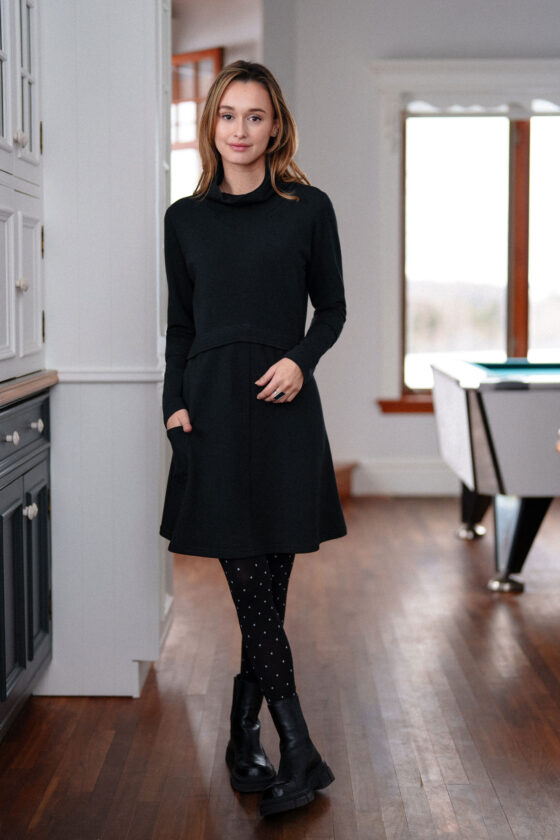 A woman wearing the Suzor Tunic-Dress by Rien ne se Perd in Black, standing by a set of cupboards