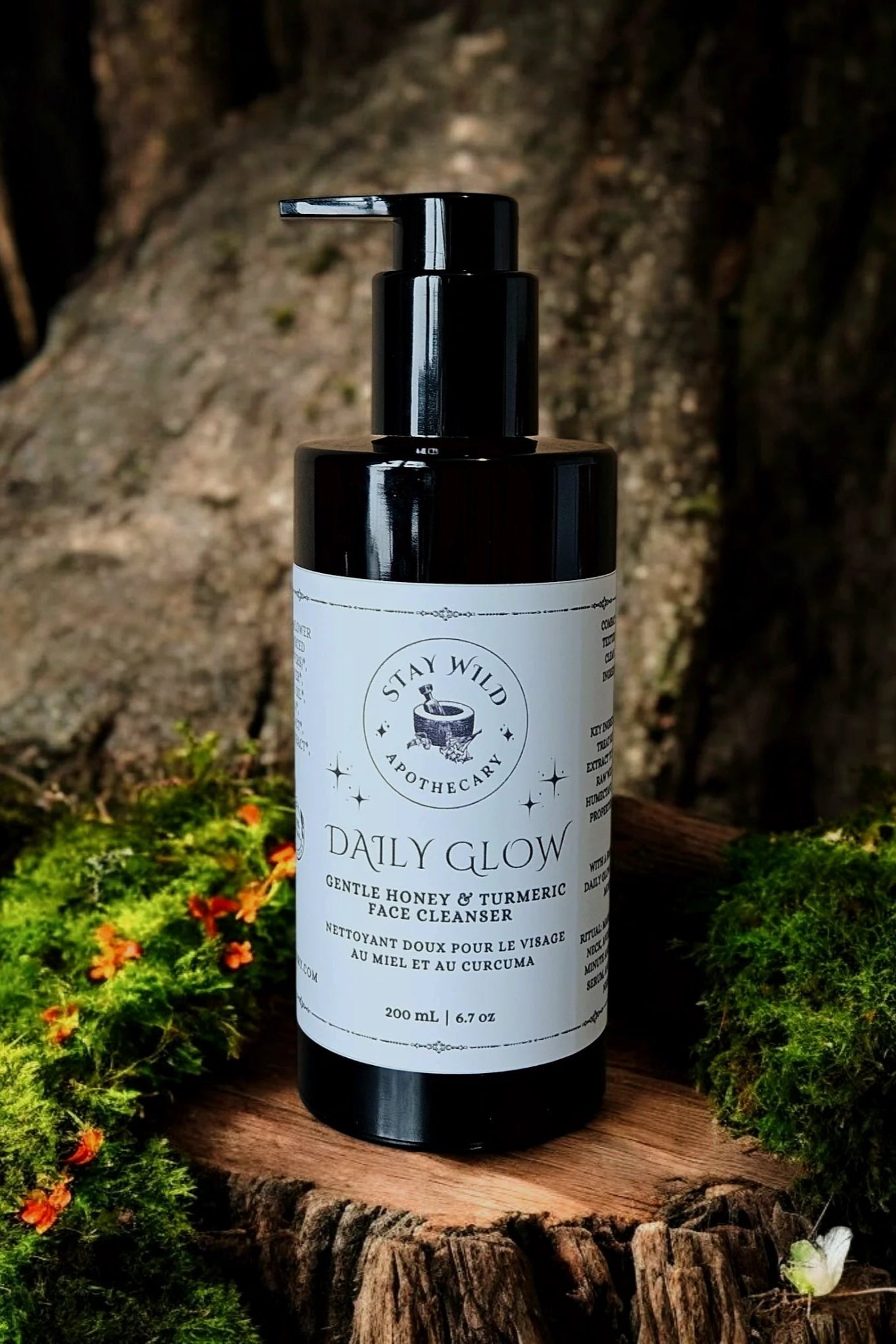 Bottle of 'Daily Glow' face cleanser by Stay Wild Apothecary, on a wooden surface with natural background