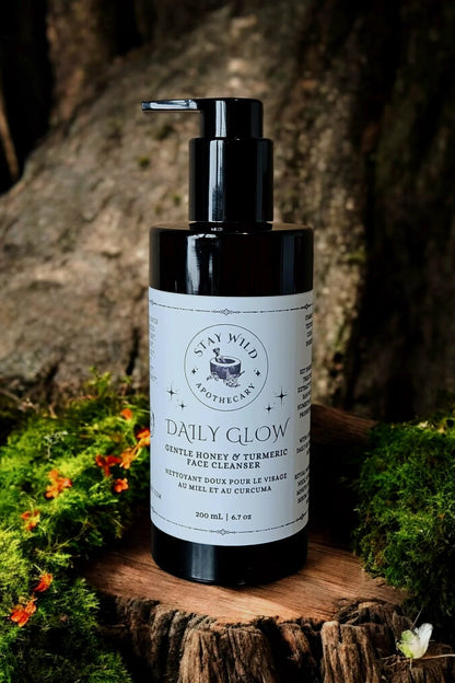 Bottle of 'Daily Glow' face cleanser by Stay Wild Apothecary, on a wooden surface with natural background