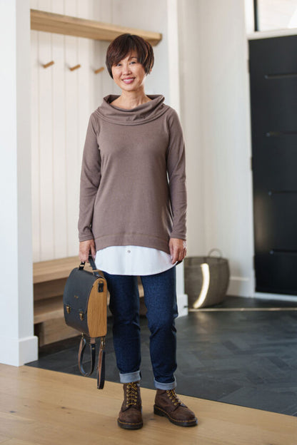 A woman wearing the Granite Pants by Rien ne se Perd in Denim Blue, standing in the entry way of a home