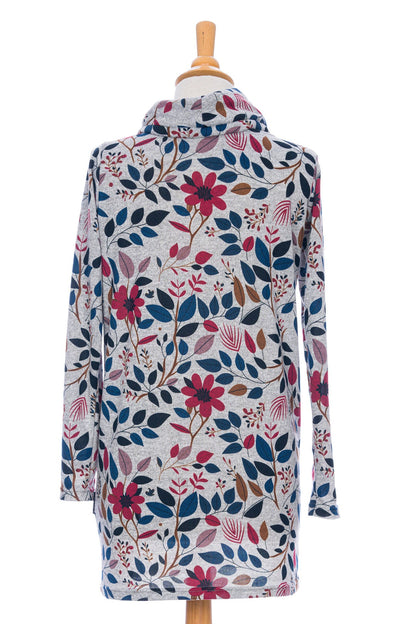 Back view of the Genevrier Tunic by Rien ne se Perd in Floral, featuring a turtleneck with a drawstring, a kangaroo pocket, long sleeves, and a straight cut, is shown on a mannequin in front of a white background. 