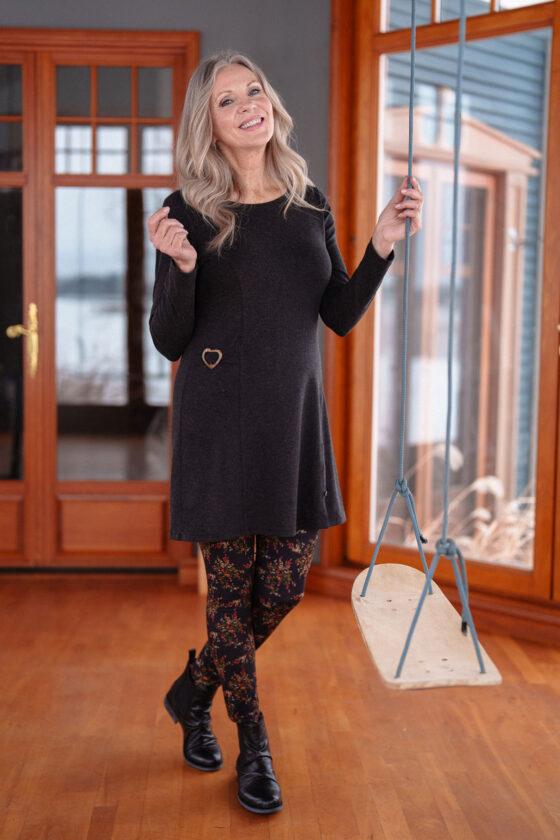 A woman wearing the Modigliani Tunic by Rien ne se Perd in Charcoal standing by an indoor swing.