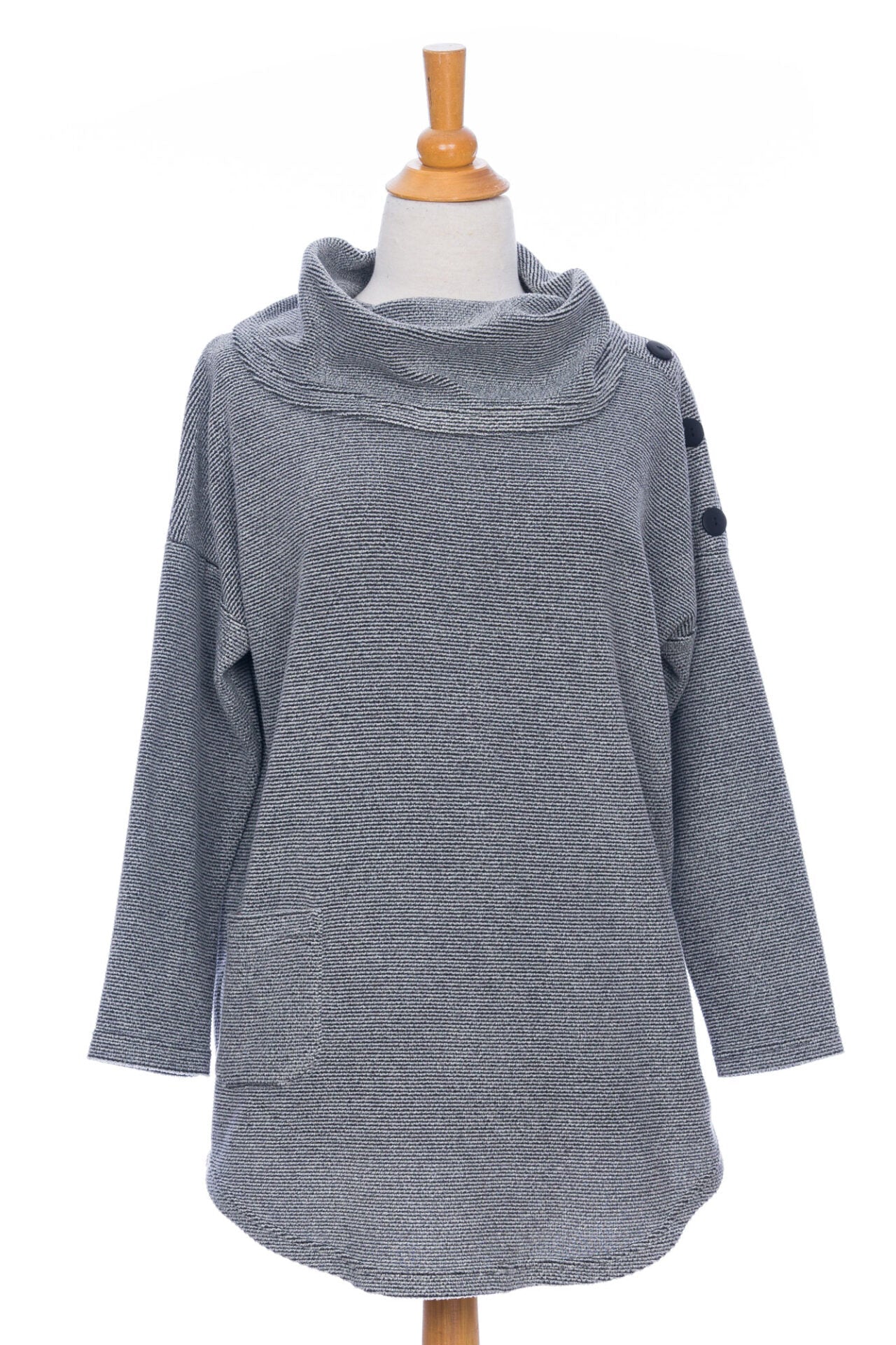 The Myrique Tunic by Rien ne se Perd in Grey, an oversized chenille tunic with a large cowl neck, rounded hem, faux leather elbow patches, button placket at the left shoulder, and patch pocket on the front, is shown on a mannequin in front of a white background. 