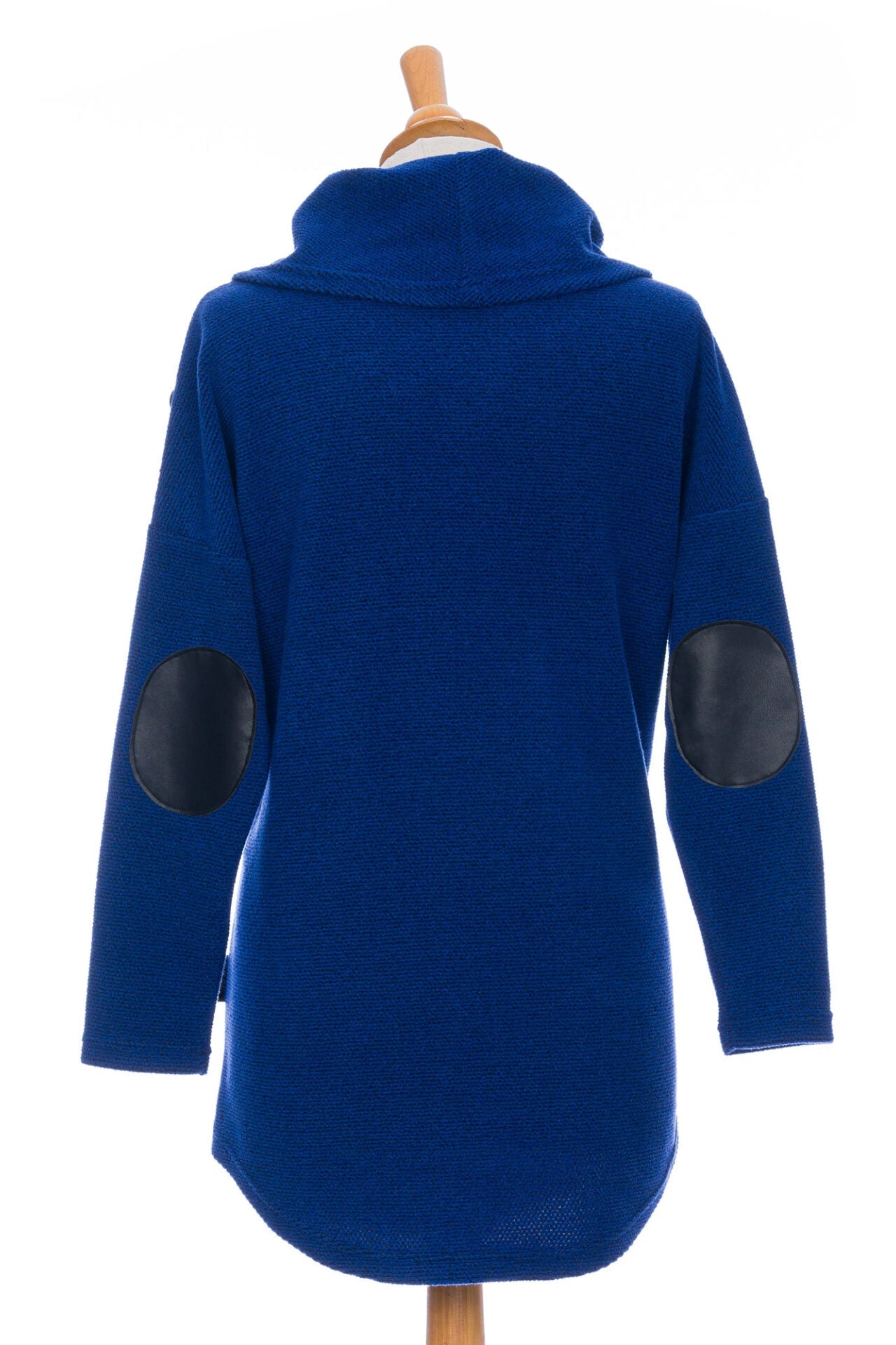 Back view of the Myrique Tunic by Rien ne se Perd in Blue, an oversized chenille tunic with a large cowl neck, rounded hem, faux leather elbow patches, button placket at the left shoulder, and patch pocket on the front, is shown on a mannequin in front of a white background. 
