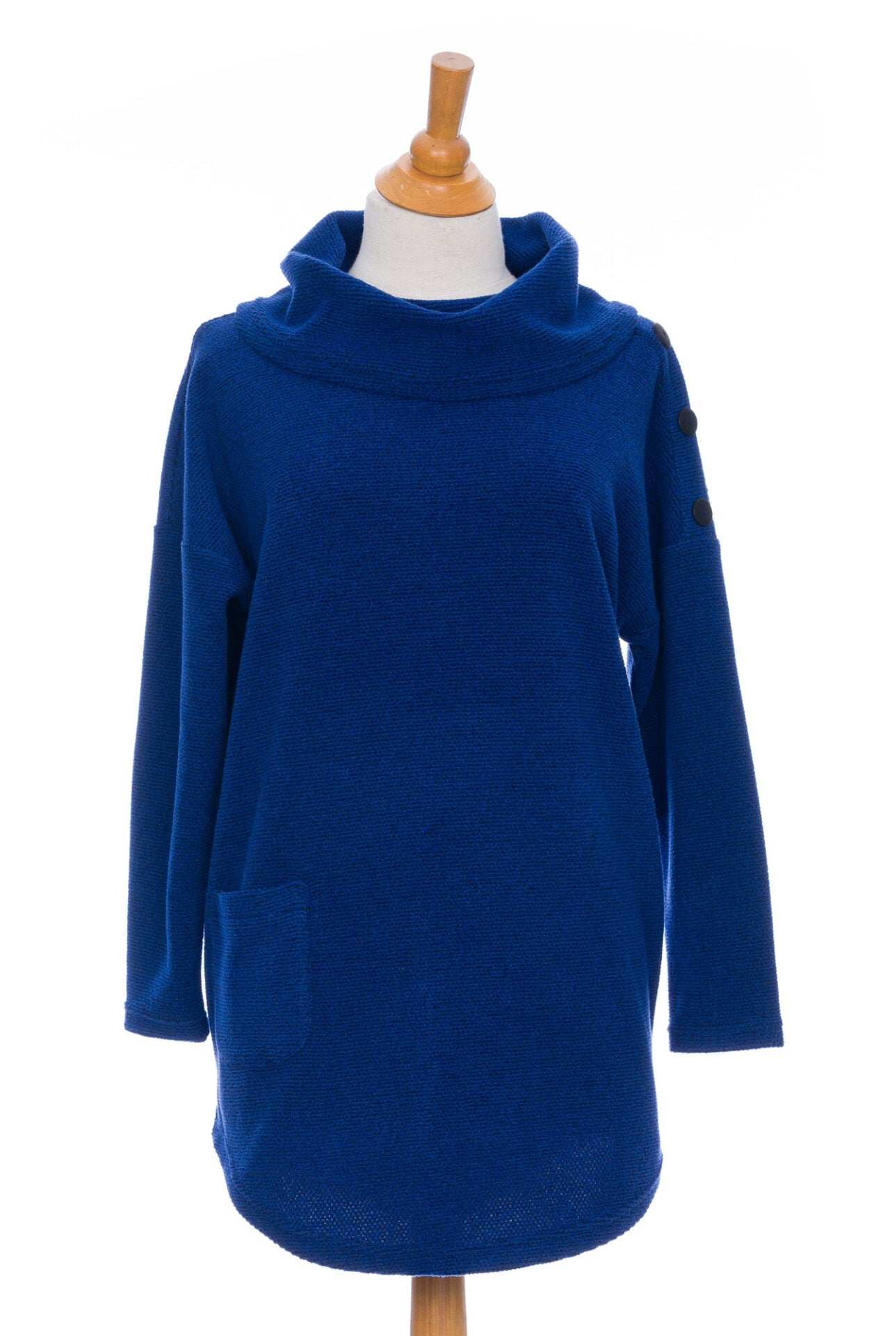 The Myrique Tunic by Rien ne se Perd in Blue, an oversized chenille tunic with a large cowl neck, rounded hem, faux leather elbow patches, button placket at the left shoulder, and patch pocket on the front, is shown on a mannequin in front of a white background. 