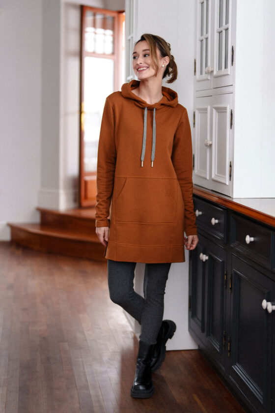 A woman wearing the Toulouse Tunic by Rien ne se Perd in Cognac, standing beside a set of cupboards