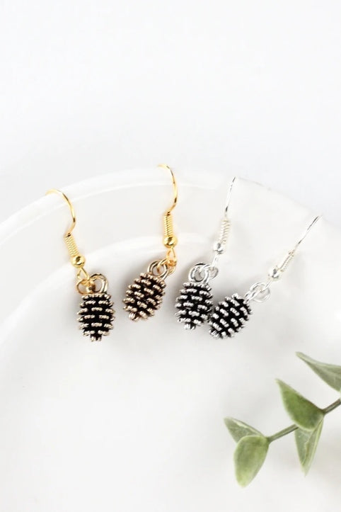 Pine cone earrings by Birch Jewellery; silver and gold; styled on a white ceramic dish