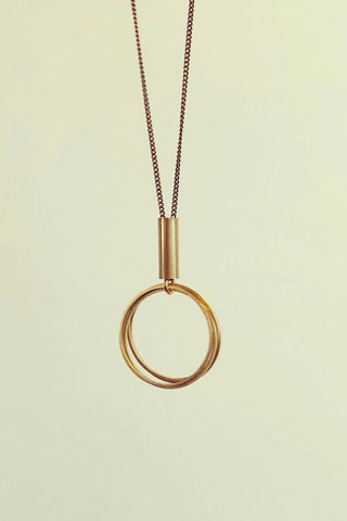 Taliah long necklace by Darlings of Denmark; raw brass; four mini thin hoops hanging off a short tube; flat lay