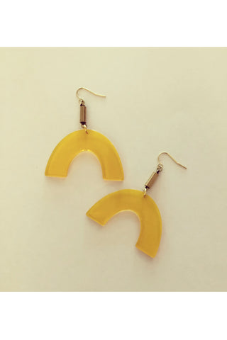 Vuttue dangle earring by Darlings of Denmark; semi-transparent yellow acrylic arch shapes hanging off raw brass tubes; flay lay